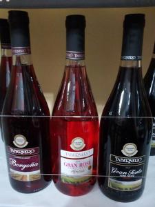 tres botellas de vino sentadas en un estante en Hostal Kmr en Chosica
