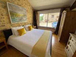 1 dormitorio con 1 cama grande con almohadas amarillas en La Porcherie, en Saint-Mathieu