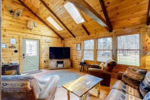 ein Wohnzimmer mit Holzwänden und einem Flachbild-TV in der Unterkunft Little Log Cabin in the Woods in The Highlands