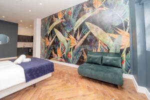a bedroom with a large mural and a green chair at NEW *SPACIOUS STUDIO *HIGH CEILING * MINS AWAY FROM BRIGHTON BEACH in Brighton & Hove
