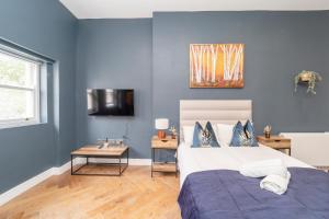 1 dormitorio con paredes azules, 1 cama y 1 mesa en NEW *SPACIOUS STUDIO *HIGH CEILING * MINS AWAY FROM BRIGHTON BEACH, en Brighton & Hove