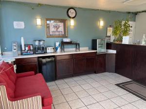 a waiting room with a red couch and a clock on the wall at Sunset Inn in Grants Pass