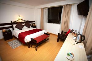 um quarto com uma cama grande e um cobertor vermelho e branco em Hotel Kapac Inn-San Blas em Cusco