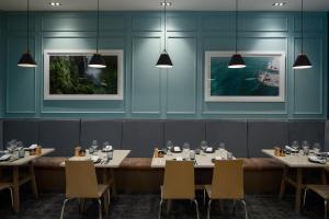 a dining room with tables and chairs and lights at Rydges Auckland in Auckland