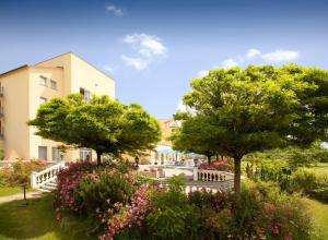 two trees and flowers in front of a building at Dorint MARC AUREL Spa & Golf Resort in Bad Gögging