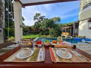 uma mesa com copos e pratos de comida e uma piscina em IN HOSPEDAGEM n45 em Paraty