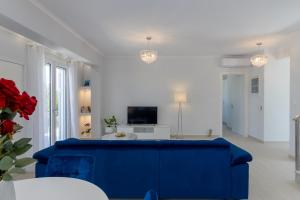 uma sala de estar com um sofá azul e uma televisão em VILLA EKTAMA em Fiskardho