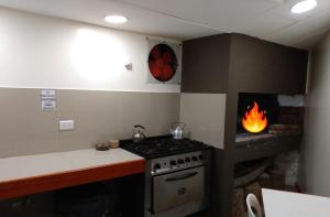 a kitchen with a stove and a fire in a fireplace at Hostería El Alemán in Cosquín