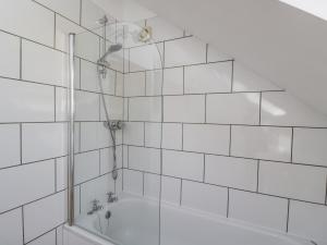 La salle de bains est pourvue de carrelage blanc, d'une douche et d'une baignoire. dans l'établissement Parkfield Cottage, à Sturminster Marshall 14 autres photos