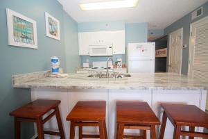 uma cozinha com um balcão e dois bancos e um balcão em Tradewinds 1102 condo em Orange Beach