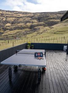 a ping pong table on a deck with a view of a field at Luxurious & Unique Villa / Nature / Beach / Hiking in Tjørnuvík