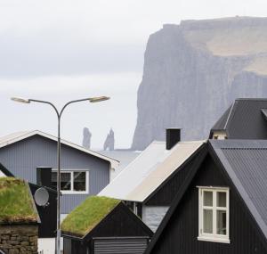 una vista de los tejados de las casas con los acantilados en el fondo en Luxurious & Unique Villa / Nature / Beach / Hiking en Tjørnuvík