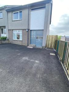 a house with a blue garage door in a parking lot at Pure Apartments Fife - Dunfermline West in Oakley