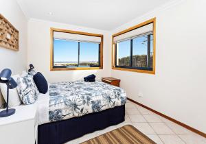 a bedroom with a bed and two windows at Allure On Seven Mile Beach Gerroa in Gerroa