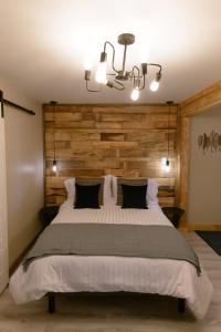 Un dormitorio con una cama grande con una pared de madera. en Le Court-Toit, en Rouyn