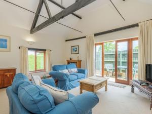 uma sala de estar com sofás azuis e uma televisão em Willow em Wood Norton