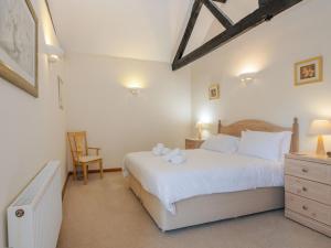 um quarto com uma grande cama branca e uma cadeira em Willow em Wood Norton