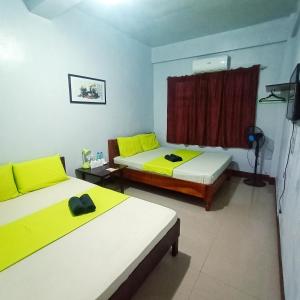 two beds in a room with yellow and white at Ahras Place in Coron