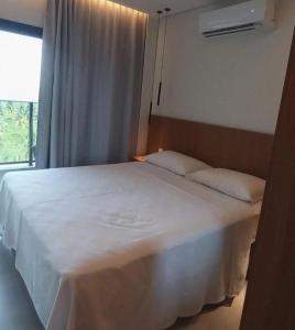 a bedroom with a large white bed with a window at Salinas Premium Resort in Salinópolis