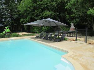 a pool with an umbrella and chairs and a table at Gîte Mauzens-et-Miremont, 6 pièces, 10 personnes - FR-1-616-254 in Mauzens-et-Miremont