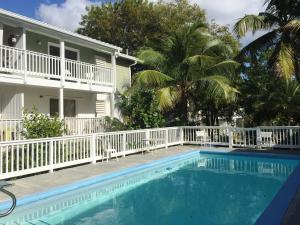 a pool in front of a house with a white fence and palm trees at Breezy Nights St. Croix in Christiansted