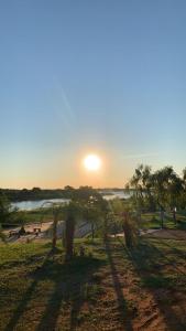 una puesta de sol sobre una playa con árboles en un campo en CostaMansa House, a orillas del Rio Paraguay, en Asunción