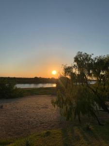 einen Sonnenuntergang über einem Wasserkörper mit einem Baum in der Unterkunft CostaMansa House, a orillas del Rio Paraguay in Asunción