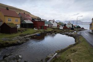 un petit village avec des maisons et une rivière dans l'établissement 4 BR House / Scenic Village / Nature / Hiking, à Við Gjógv