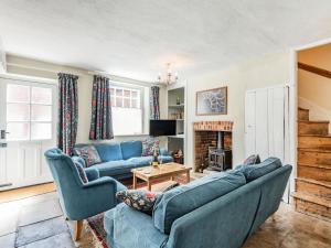 uma sala de estar com sofás azuis e uma lareira em Ammonite Cottage em Wareham
