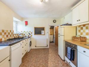 uma cozinha com armários brancos e um forno com placa de fogão em Ammonite Cottage em Wareham