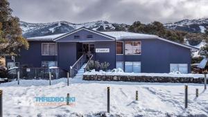 ein blaues Haus im Schnee mit Bergen im Hintergrund in der Unterkunft Steamboat 2 in Thredbo