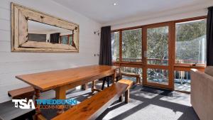 ein Esszimmer mit einem Holztisch und einem Spiegel in der Unterkunft Steamboat 2 in Thredbo