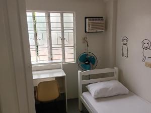 um pequeno quarto com uma cama e uma janela em Bed and Brewhouse Sucat em Manila