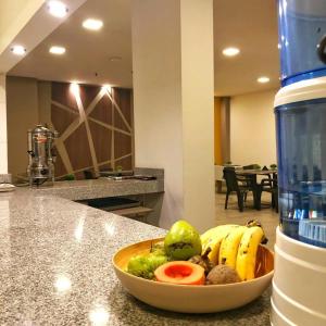 HM HOTEL Expo Inn في بوغوتا: وعاء من الفواكه على منضدة بجوار زجاجة المياه