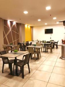 a restaurant with tables and chairs and a flat screen tv at HM HOTEL Expo Inn in Bogotá