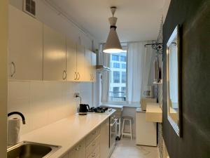 een keuken met witte kasten, een wastafel en een raam bij Perfect location two bedrooms with balkony in Warschau