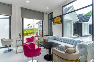 a living room with a couch and pink chairs at The Chill Villa Prachuap in Khao Khan Kradaj