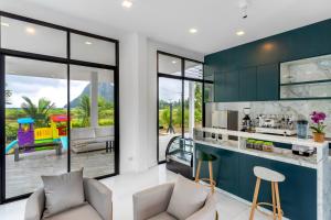a living room with green cabinets and a kitchen at The Chill Villa Prachuap in Khao Khan Kradaj