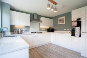 a kitchen with white cabinets and green walls at New Build 5 Bedroom Detached House With Parking in Bicester