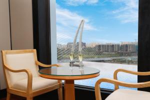 ホーチミン・シティにあるLotte Hotel Saigonの窓際のテーブルにワイン2杯