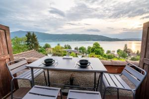 einen Tisch und Stühle auf einem Balkon mit Blick auf das Wasser in der Unterkunft CABANA & Sunset - Terrasse , Parking & Lac in Veyrier-du-Lac