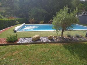 a swimming pool with a tree and rocks in a yard at Entre Lacs et Montagnes 