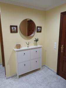 een badkamer met een witte dressoir en een spiegel bij Parque de los Patos in Cedeira