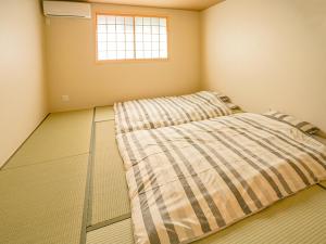 ein Bett in einem Zimmer mit Fenster in der Unterkunft 慶有魚·八坂(Kyotofish·Yasaka)*近清水寺祗园5分钟*庭院地暖浴缸*京都民宿认证 in Kyoto