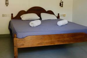 a large wooden bed with two pillows on it at Freedom Beach Arugam Bay in Arugam Bay