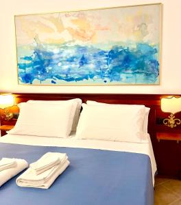 a bed with white pillows and a painting above it at Hotel Villa Cute - HVC in Lipari