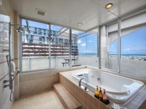 ein Bad mit einer Badewanne und Meerblick in der Unterkunft HOTEL PACIFIC VIEW（ホテルパシフィックビュー） in Okinawa