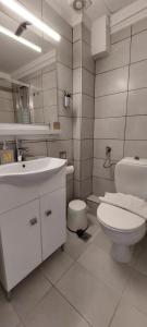 a white bathroom with a toilet and a sink at VitaminSea Apartments in Kallithea Halkidikis