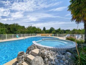 a swimming pool with rocks around it at Gîte le Chêne Vert in a holiday park with pool in Saint-Savinien