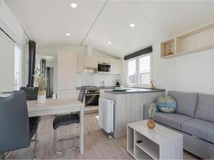 een keuken en een woonkamer met een bank en een tafel bij Modern mobile home in Middelkerke with garden in Middelkerke